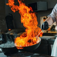 Un chef tient un wok enflammé