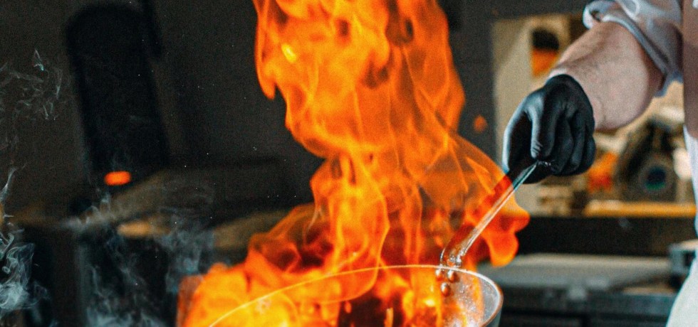 Un chef tient un wok enflammé