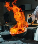 Un chef tient un wok enflammé